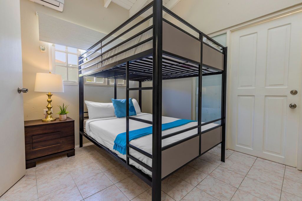 Dormitorio con literas, mesita de noche y una puerta.