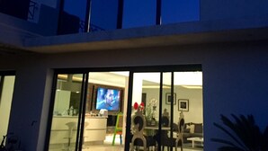 A modern house with large windows, a visible living room with a TV, and a dining area with chairs and a table. - Luxury loft with pool and garden (Avignon)