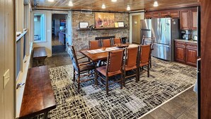 Una cocina amplia con armarios de madera, un comedor con una mesa grande y sillas, y una chimenea de piedra.