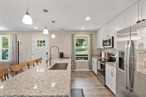 A modern kitchen with granite countertops, stainless steel appliances, and pendant lighting.