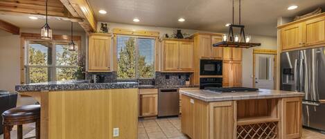 A spacious kitchen with wooden cabinetry, a large island, stainless steel appliances, and pendant lighting.