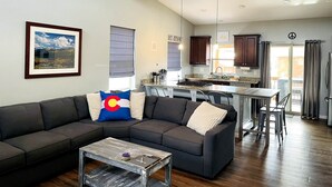 A modern living room with a sectional sofa, a coffee table, and a ceiling fan. - The Aspen - in WPCO at 8488 ft elevation (Woodland Park)