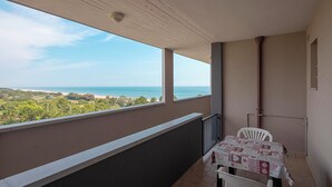 A balcony with a table and chairs, overlooking a coastal view. - [lido Adriano Free Parking]appartamento SUL Mare (Lido Adriano)