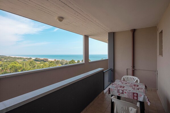 Een balkon met een tafel en stoelen, met uitzicht op de kust.