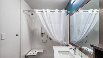 Un baño moderno con ducha, lavabo y espejo.