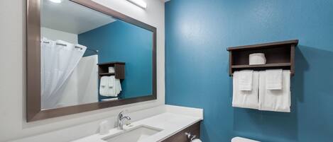 A bathroom with a white sink, a mirror, a blue wall, a toilet, and a towel rack.