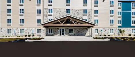 A multi-story hotel with a stone facade, a central entrance, and a parking lot.