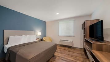 Une chambre d’hôtel équipée d’un lit, d’une télévision, d’une chaise, d’un bureau et d’une fenêtre avec des stores.
