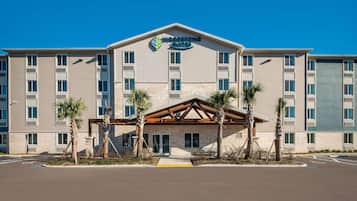 Experience the modern design of Woodspring Suites, featuring a central entrance and multiple windows on each floor.