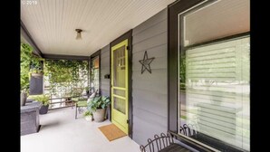 Un porxo cobert amb una porta verda, plantes en testos i una decoració d'estrella.