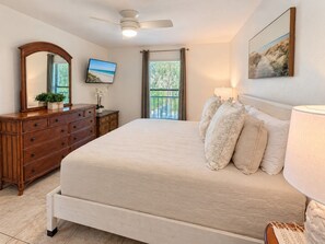 A bedroom with a bed, dresser, mirror, television, and a window with a view. - Park Shore Resort-2nd Floor BLDG J #255*Lake view* (Park Shore Resort)