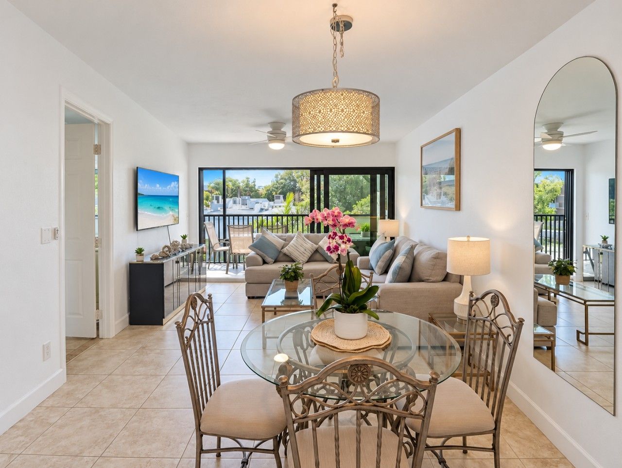 A spacious living area with a glass dining table, comfortable seating, a large sofa, and a view of the outdoors.