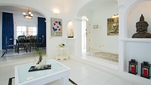Un amplio espacio de estar con un comedor, una chimenea blanca y una estatua de Buda.