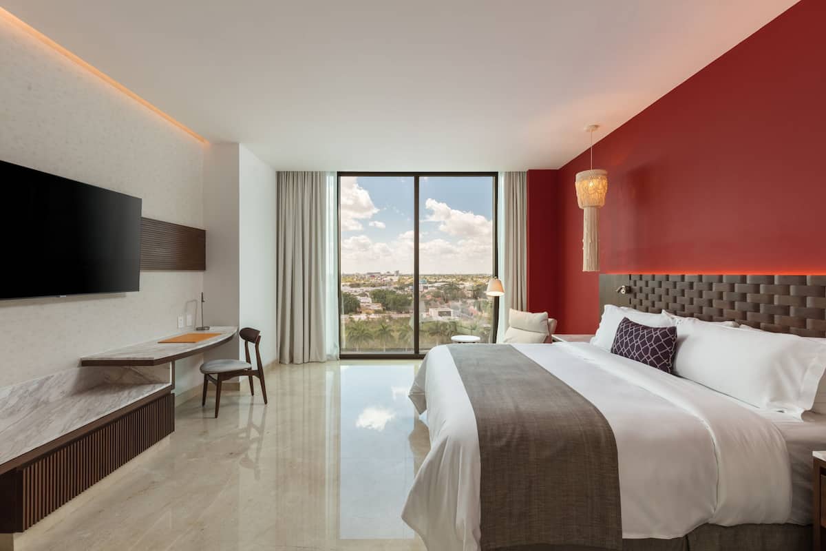 A modern hotel room with a large bed, a desk, and a TV mounted on the wall.
