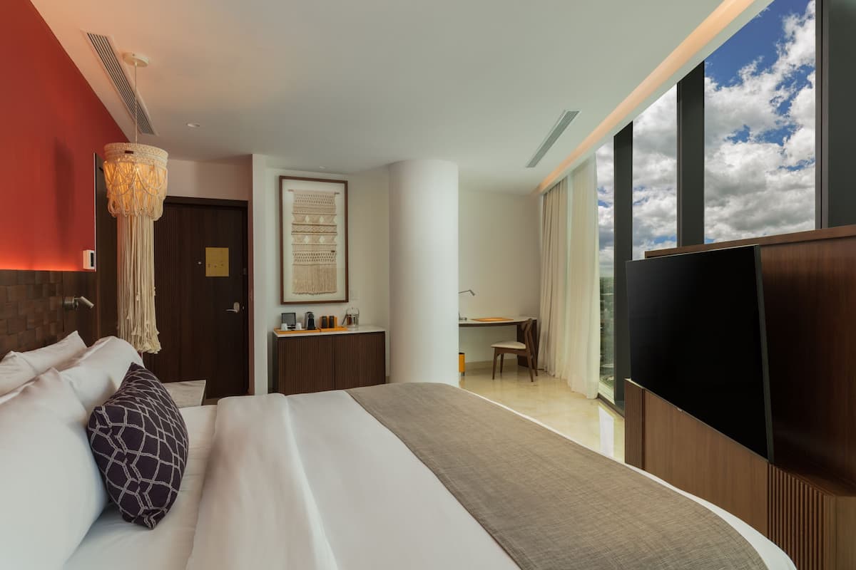 A modern hotel room with a large bed, a desk, and a TV.