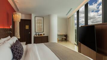 A modern hotel room with a large bed, a desk, and a TV.