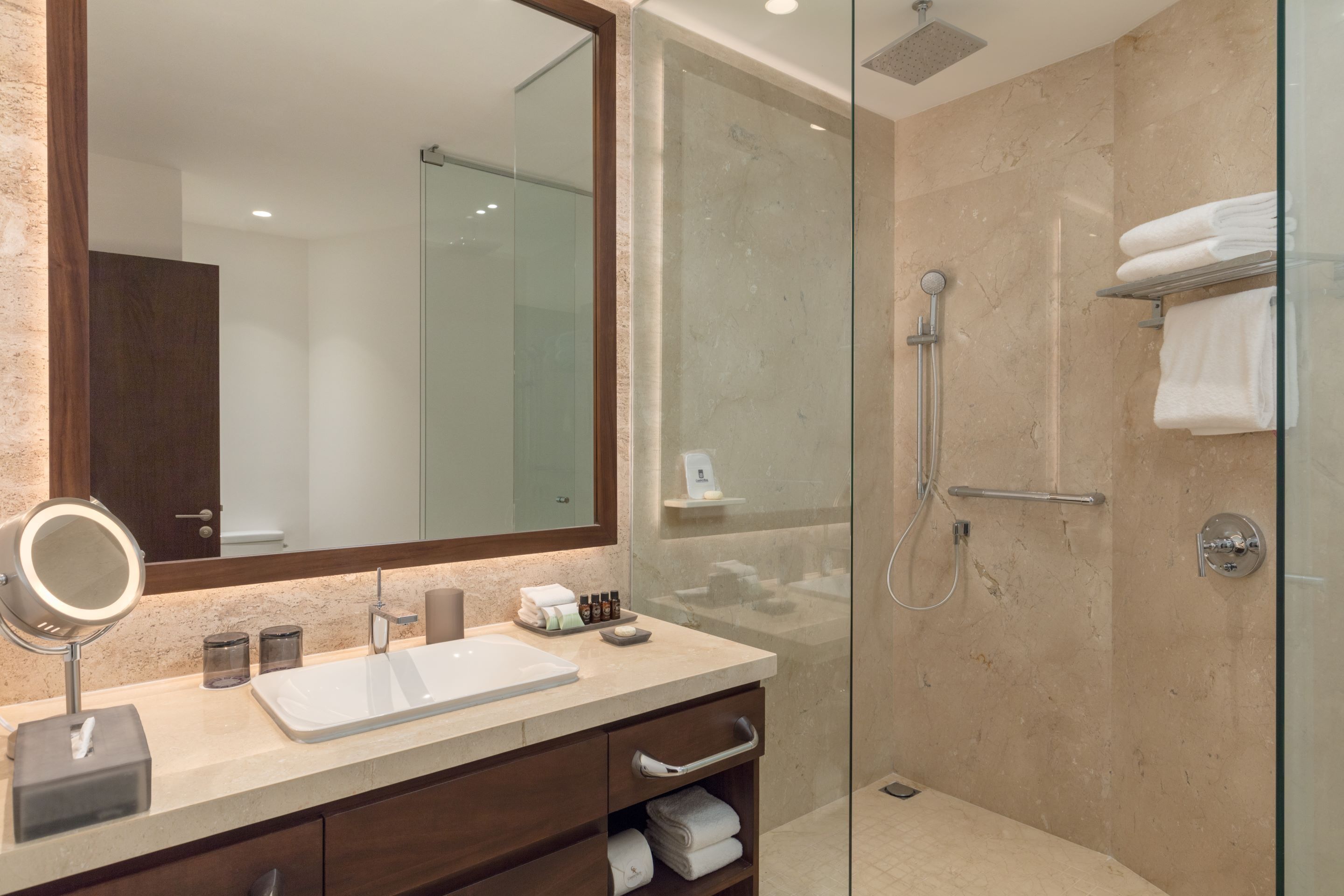 Un baño moderno con ducha de vidrio, un espejo grande y encimera de mármol.