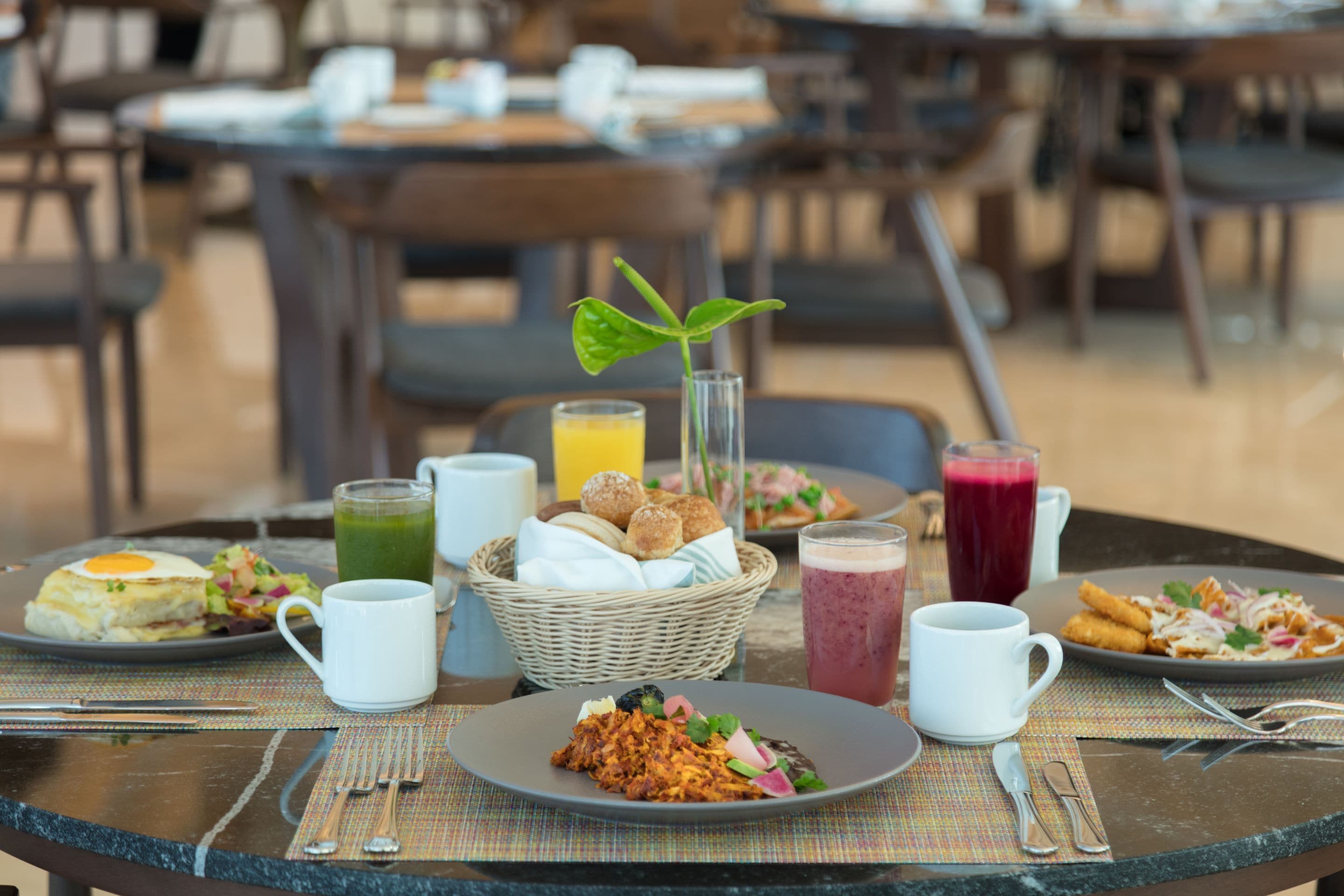 Una mesa de comedor con alimentos para el desayuno, como huevos, pan y diferentes bebidas.