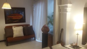 Una sala de estar con un sofá, una mesa, una lámpara, una guitarra y un cuadro en la pared.