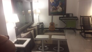 Una sala de estar con televisor, guitarra, teclado y sofá.