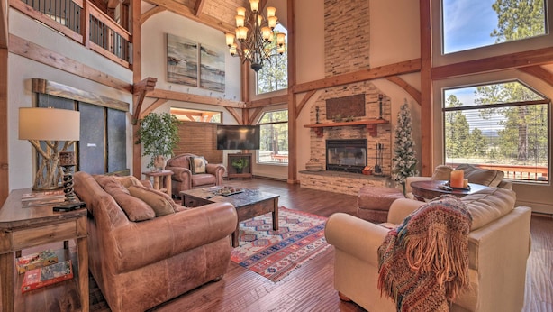 A spacious living room with a fireplace, wooden beams, and large windows. - Grand Angel Fire Retreat w/ Hot Tub & Fire Pit! (Angel Fire)