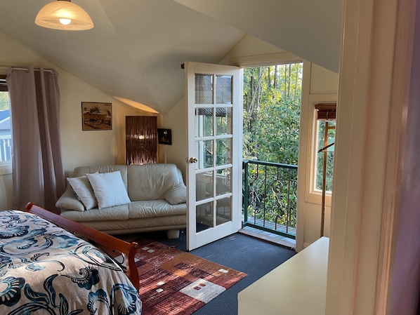 A bedroom with a sofa, a bed, a patterned rug, a door leading to a balcony with a view of trees. - Beautiful and comfortable, located in the heart of town (TAWONGA SOUTH)