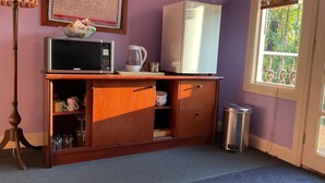 Une cuisine équipée d’un four à micro-ondes, d’une bouilloire et d’un réfrigérateur, le tout installé sur un meuble en bois.