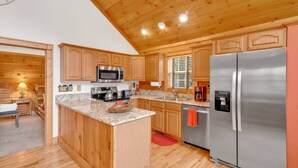 Uma cozinha rústica estilo cabana com uma ilha central, eletrodomésticos embutidos e um espaço de estar aconchegante.
