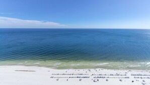 Ein Strand mit Reihen von Liegestühlen und Sonnenschirmen, einem klaren blauen Himmel und ruhigem Meer.