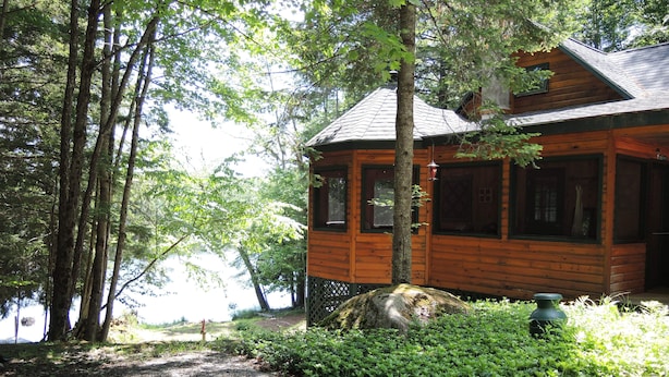Eine Holzhütte mit Kiesweg, umgeben von Bäumen und einem kleinen Garten.