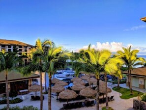 Relax by the pool surrounded by palm trees and thatched umbrellas.