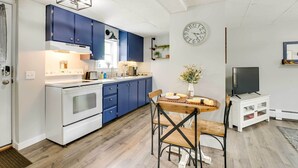 Eine moderne Küche mit blauen Schränken, einem weißen Herd und einem Essbereich mit einem Holztisch und Stühlen.