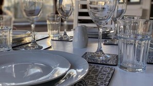 A dining table set with plates, glasses, and water glasses, with patterned placemats and a view of the outdoors through large windows. - Immaculate 2-bed Static Caravan Near the Lake (Millom)