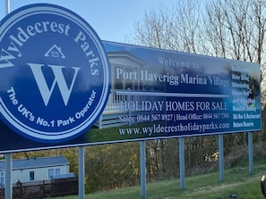 A sign for Wyldecrest Parks, highlighting features like a holiday homes for sale, contact information, and amenities such as wakeboarding, water skiing, and a ski bar & restaurant. - Immaculate 2-bed Static Caravan Near the Lake (Millom)
