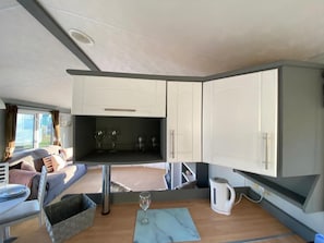 A compact RV interior with a kitchenette, a dining area, and a seating area with a sofa and table. - Immaculate 2-bed Static Caravan Near the Lake (Millom)