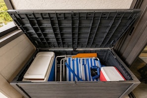 A storage box with a metal rack, a white container, a blue and white striped bag, and a red and white object. - Park Shore Resort, Top Floor BLDGH #347-Lake view (Park Shore Resort)