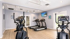Een sportschool thuis met loopbanden, een elliptische trainer en een hometrainer.