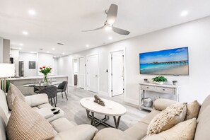 A modern living room with a sofa, a coffee table, and a television mounted on the wall. - Park Shore Resort, Top Floor BLDGH #347-Lake view (Park Shore Resort)