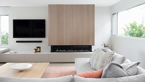 Ein modernes Wohnzimmer mit Flachbildfernseher, Kamin und großem Fenster.