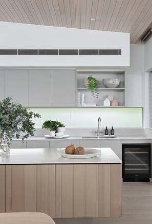 Une cuisine moderne dotée d’un îlot central, d’appareils électroménagers intégrés et d’un design minimaliste.