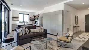 A modern living room with a sofa, armchair, and coffee table. There is a kitchen area with cabinets and a microwave. - Luxury Pet Friendly Condo, Downtown Asheville with Heated Balcony (Asheville)