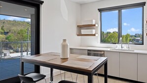 A modern kitchen with a large window, a dining area with two chairs, and a view of a green landscape. - Luxury Pet Friendly Condo, Downtown Asheville with Heated Balcony (Asheville)