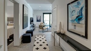 A modern hotel hallway with a minimalist design, featuring a black and white patterned rug, a dining area with a table and chairs, and artwork on the walls. - Luxury Pet Friendly Condo, Downtown Asheville with Heated Balcony (Asheville)