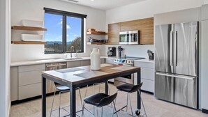 A modern kitchen with a large window, stainless steel appliances, and a wooden dining table. - Luxury Pet Friendly Condo, Downtown Asheville with Heated Balcony (Asheville)