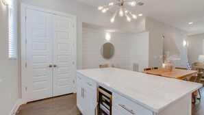A modern kitchen with white cabinetry, a marble countertop, and a unique light fixture.