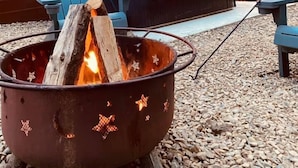 A cozy outdoor seating area with a fire pit, blue Adirondack chairs, and a wooden deck. - Romantic Splash Brand New 1 Bedroom Efficiency Cabin, near Broken Bow Lake (Broken Bow)