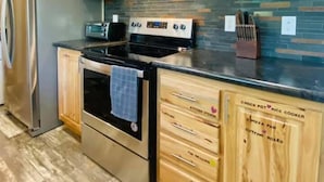 A modern kitchen with wooden cabinets, a stainless steel refrigerator, and a built-in oven. - Romantic Splash Brand New 1 Bedroom Efficiency Cabin, near Broken Bow Lake (Broken Bow)