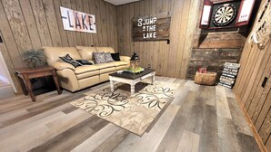 A cozy living room with a wooden wall, a couch, a coffee table, and a dartboard. - The Flippin Fisherman  (Flippin)