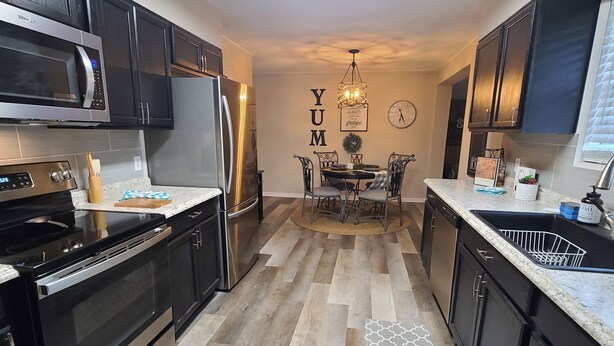 A modern kitchen with dark cabinetry, stainless steel appliances, and a dining area with a central table and chairs. - The Flippin Fisherman  (Flippin)