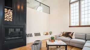 A modern living room with a fireplace, a sofa, a coffee table, and a large window.